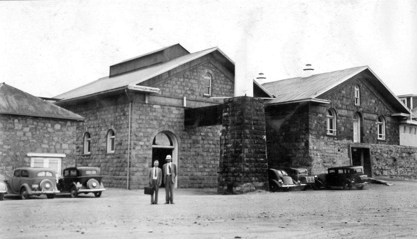 Two employees stand outside the Three Stone Buildings in 1938