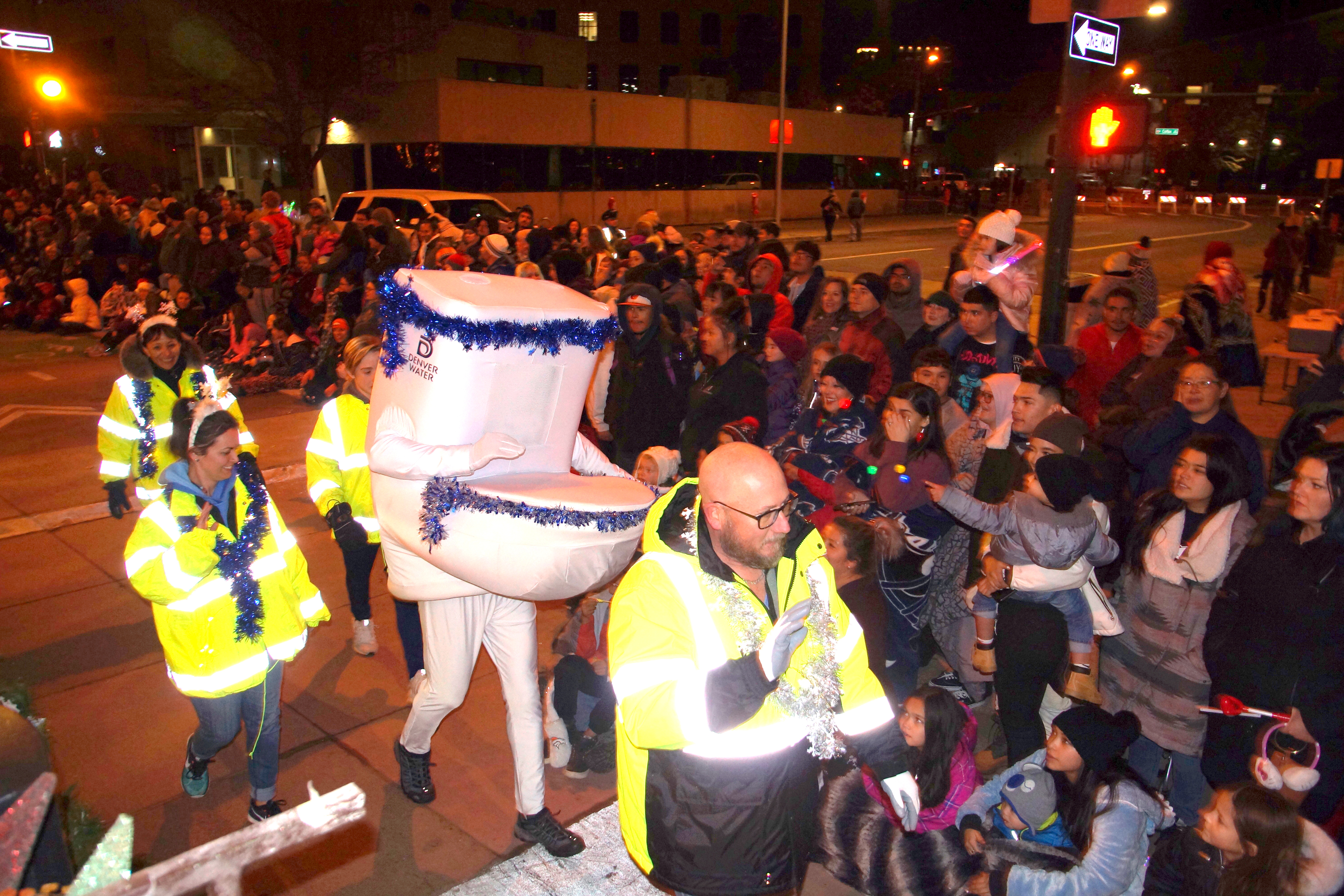 A man in a toilet costume walks with other volunteers from Denver Water surrounded by the crowd that lined the parade route.