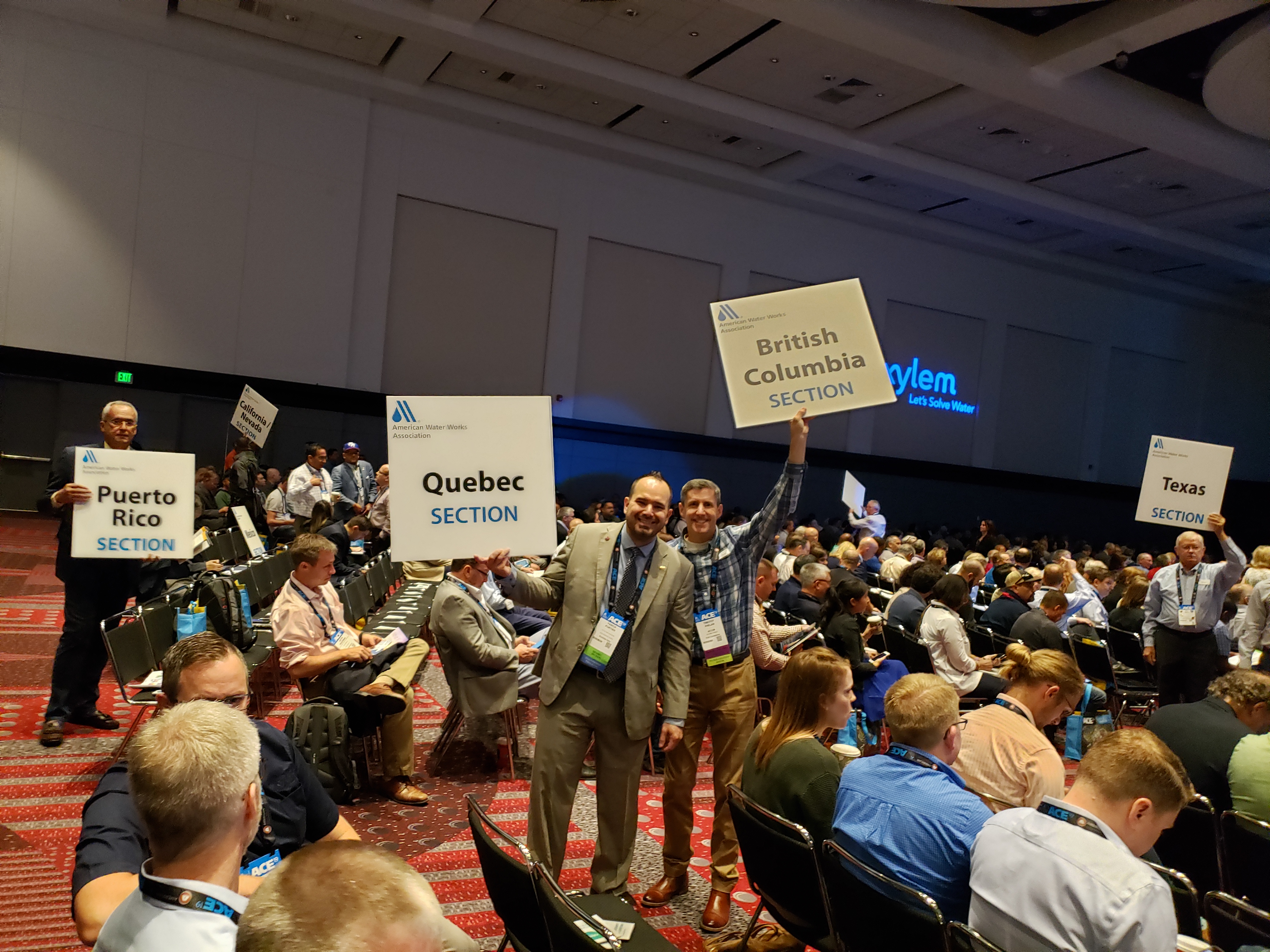 Signs for Puerto Rico, Quebec, British Columbia, Texas and California-Nevada sections of the American Water Works Association can be seen in a crowded ballroom.