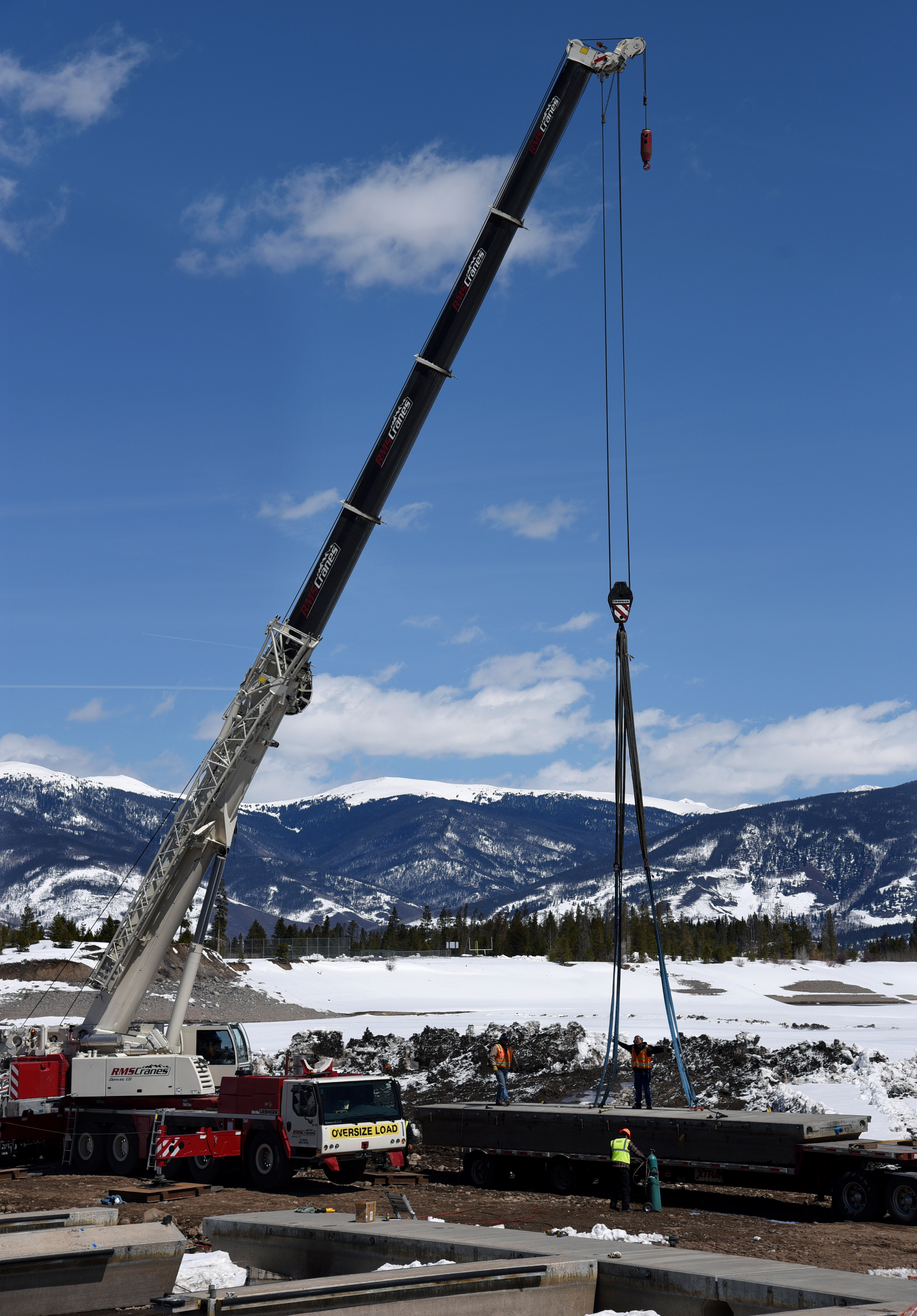A crane picks up a giant slab of concrete under blue skies.