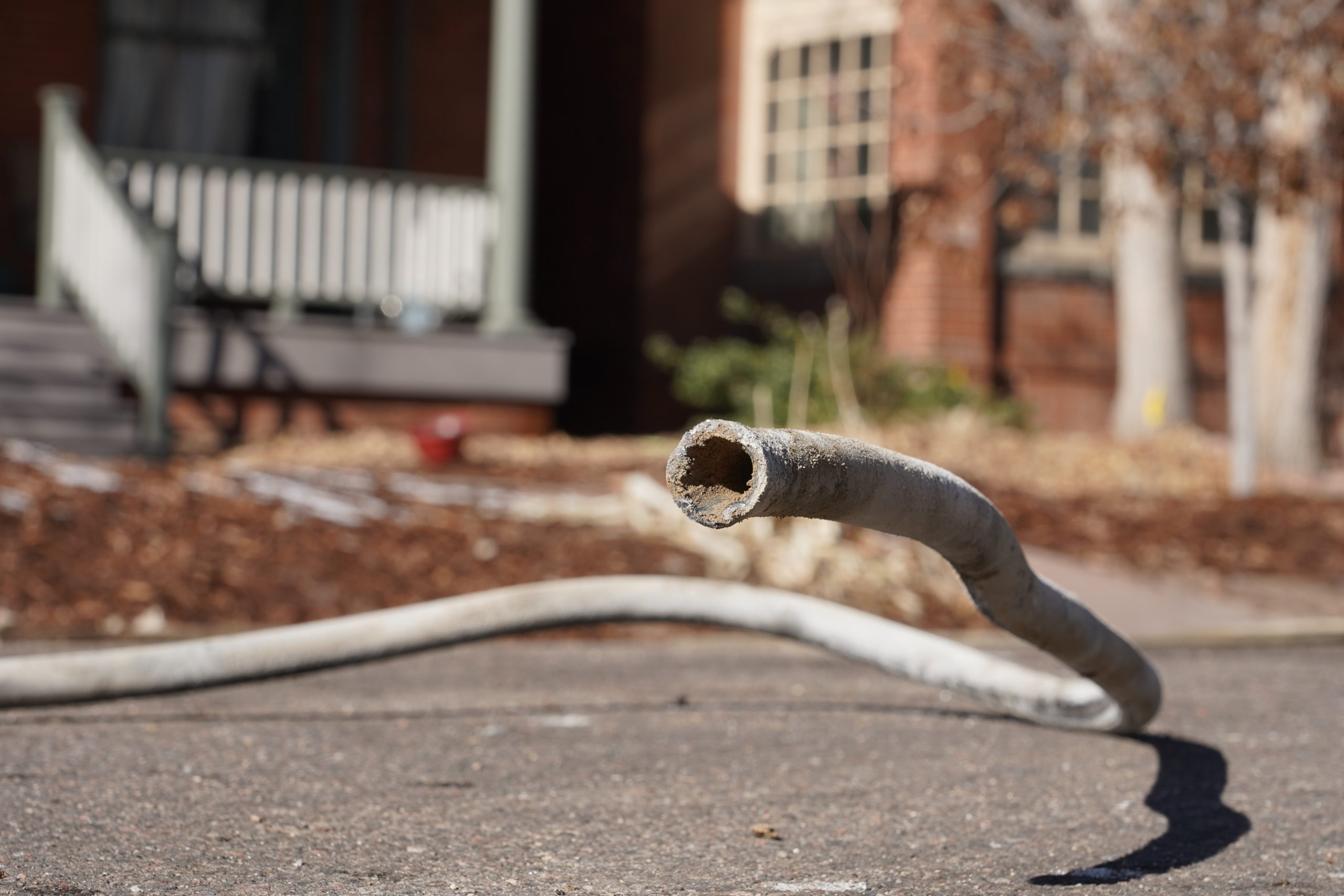 A pipe laying in the street in front of a home.