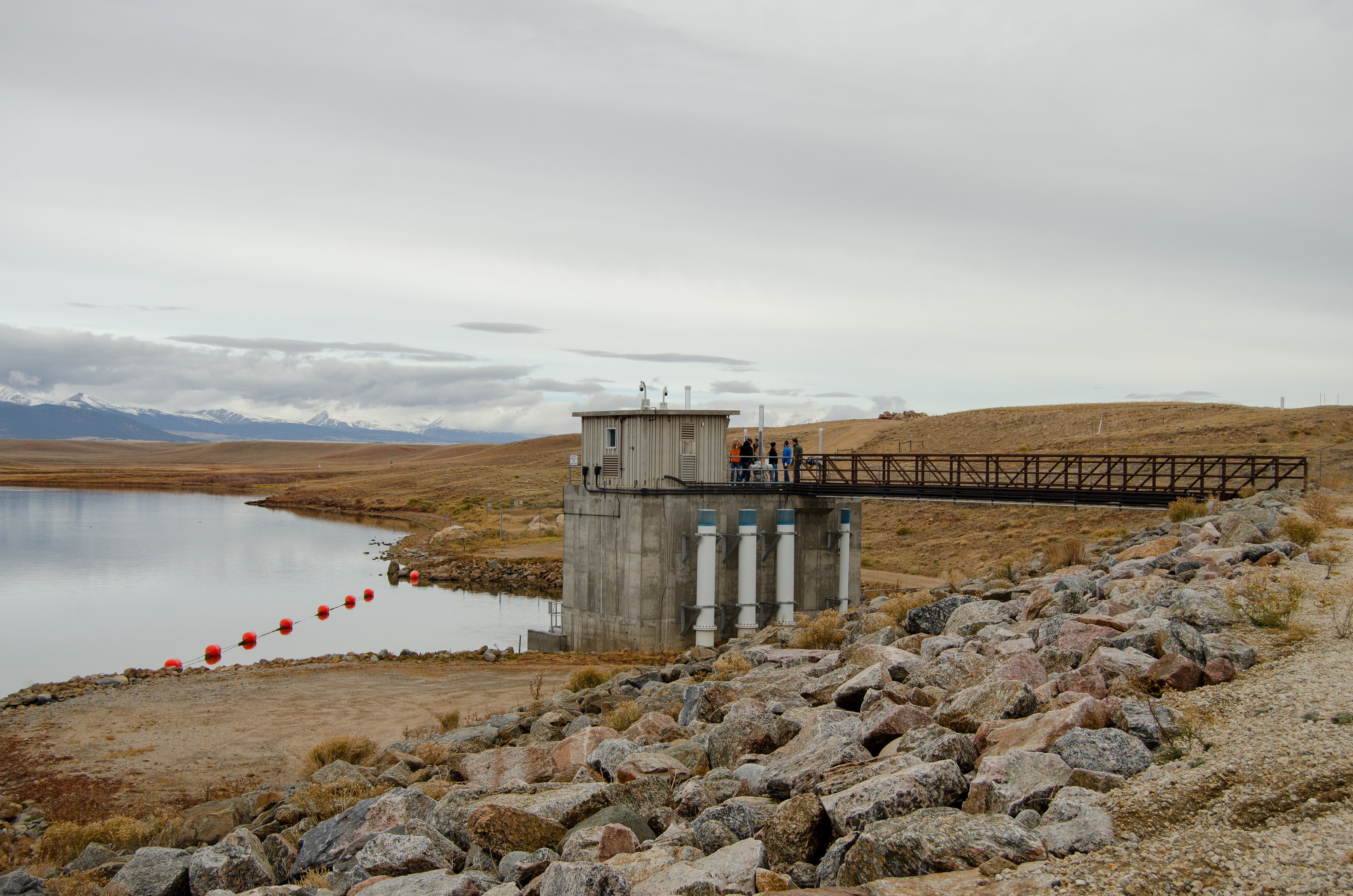 People stand on a bridge looking at equipment that is part of the Antero Reservoir dam.