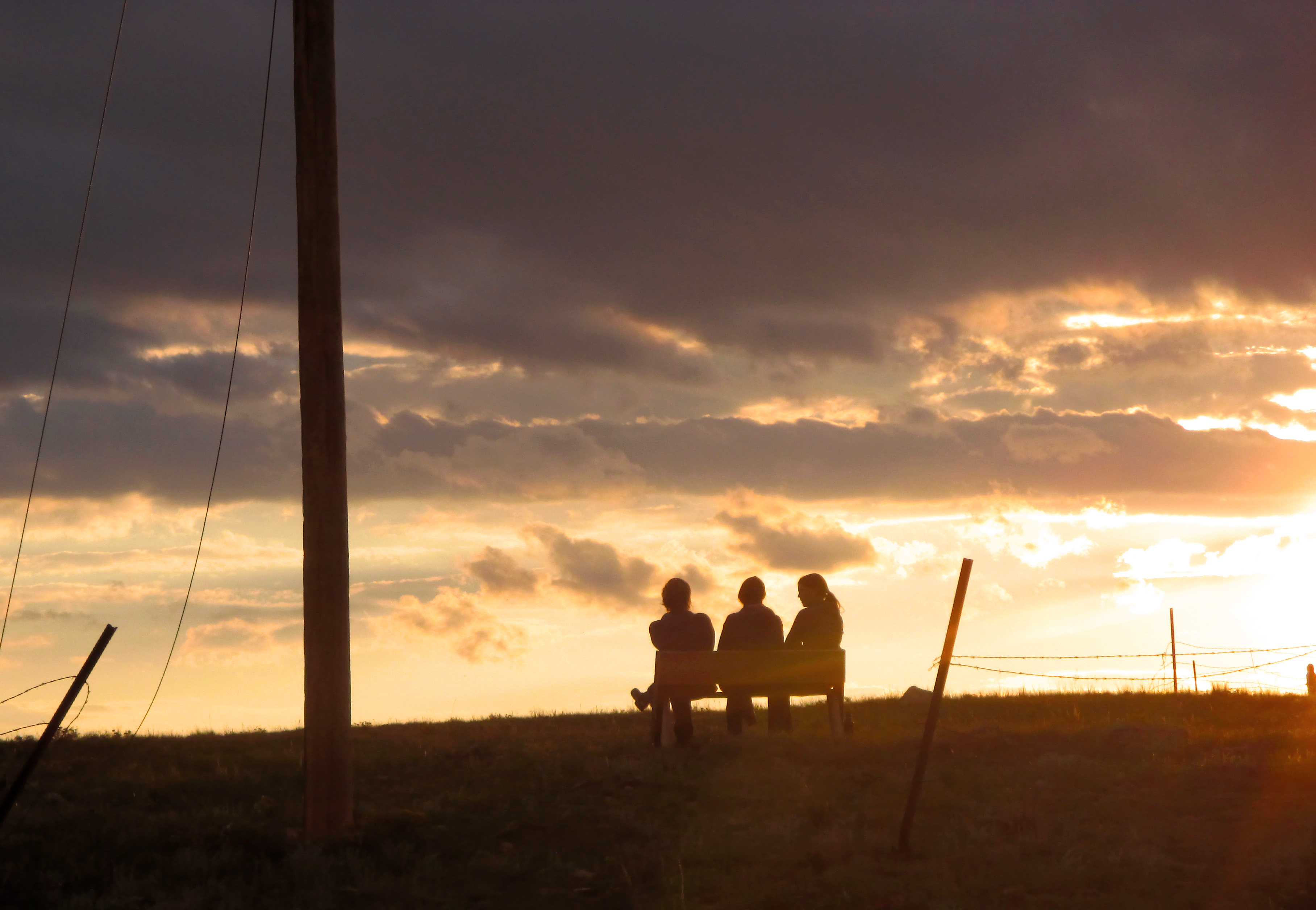 Educators sit on a bench as the sun sets over Buffalo Peaks Ranch.