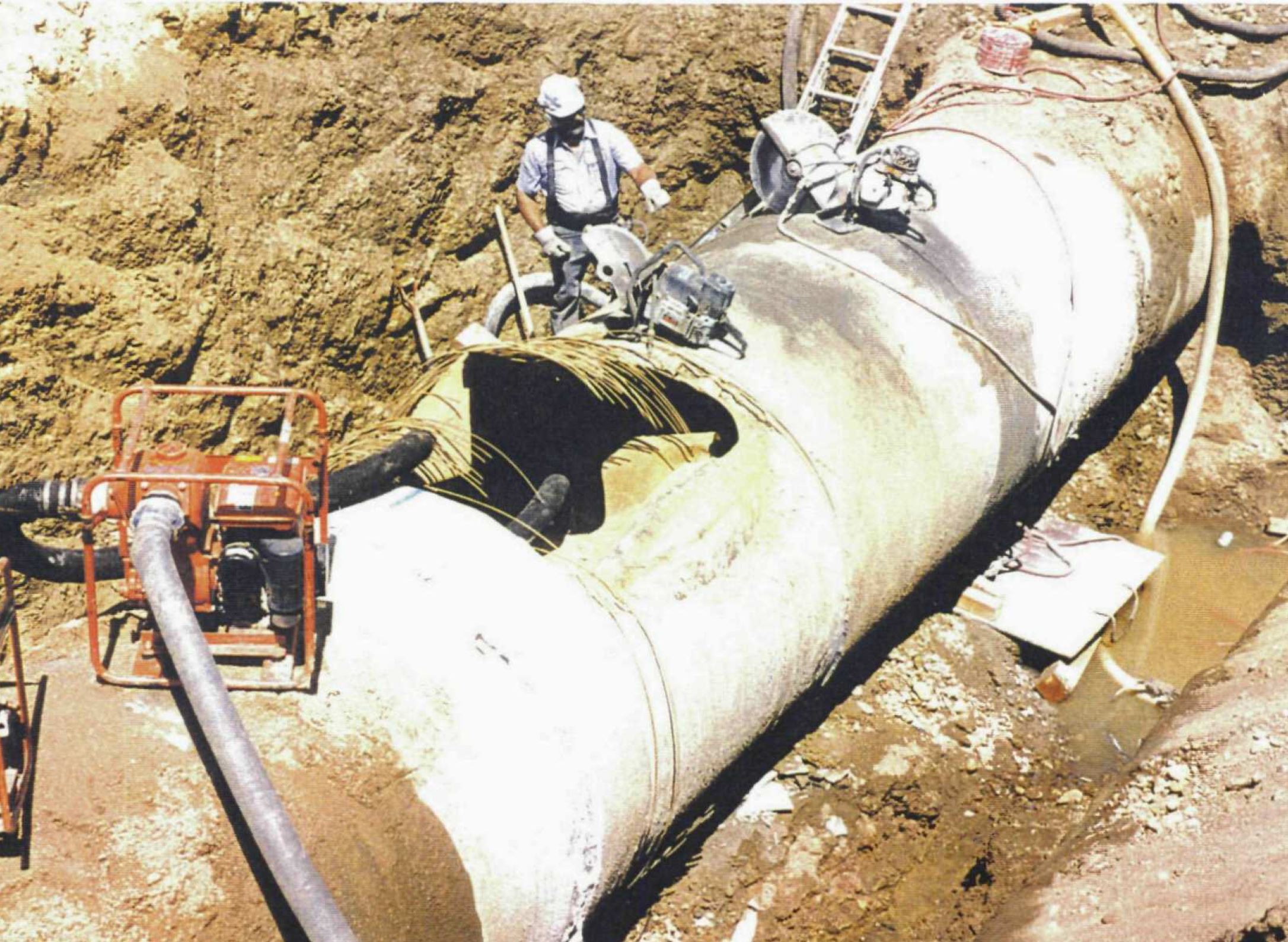 A worker prepares to cut out a section of the ruptured water pipe in 1997. You can see the broken strands of wire on the top of the pipe. Photo credit: Denver Water.