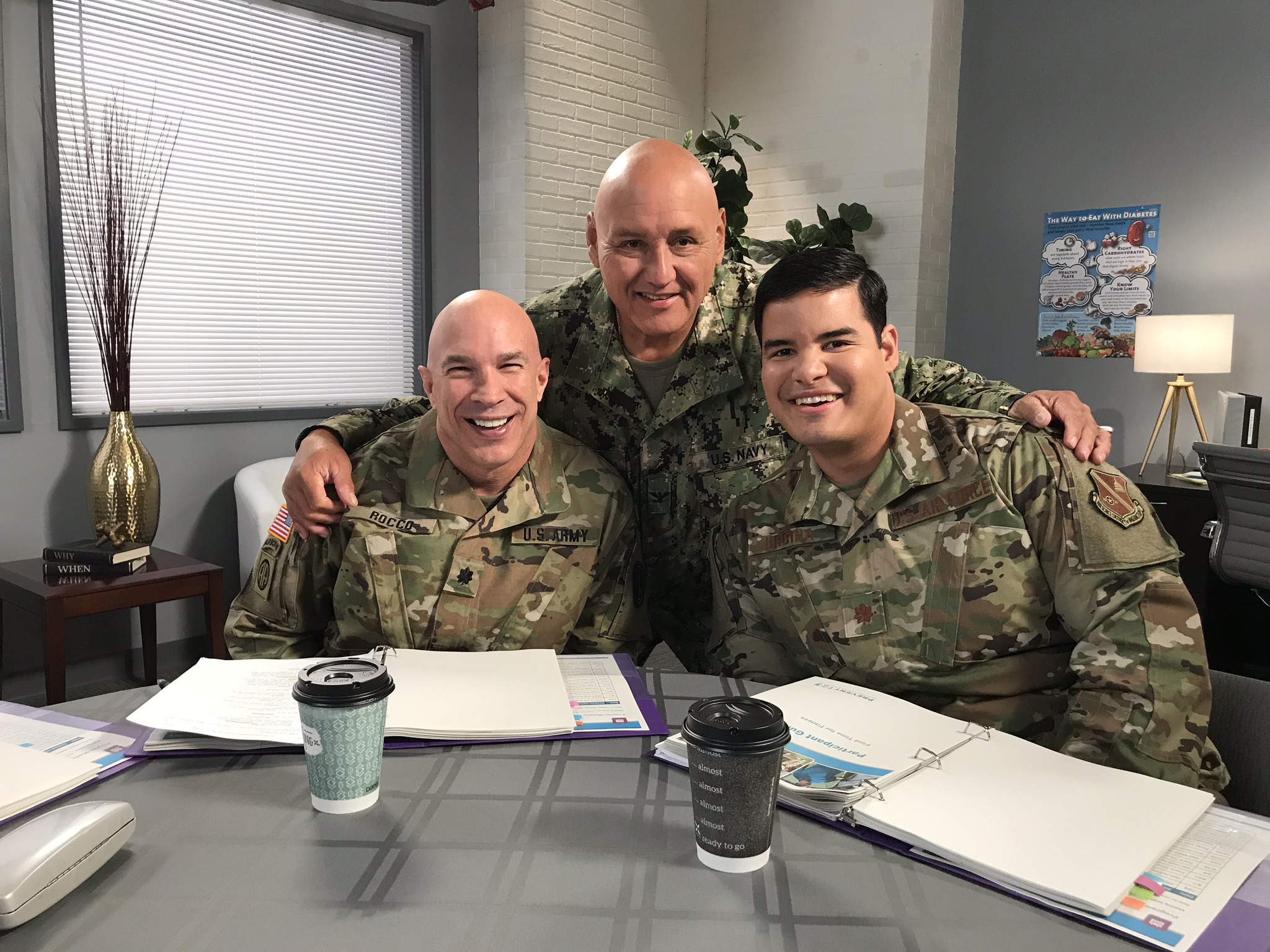 Three men in military fatigues smile for the camera.