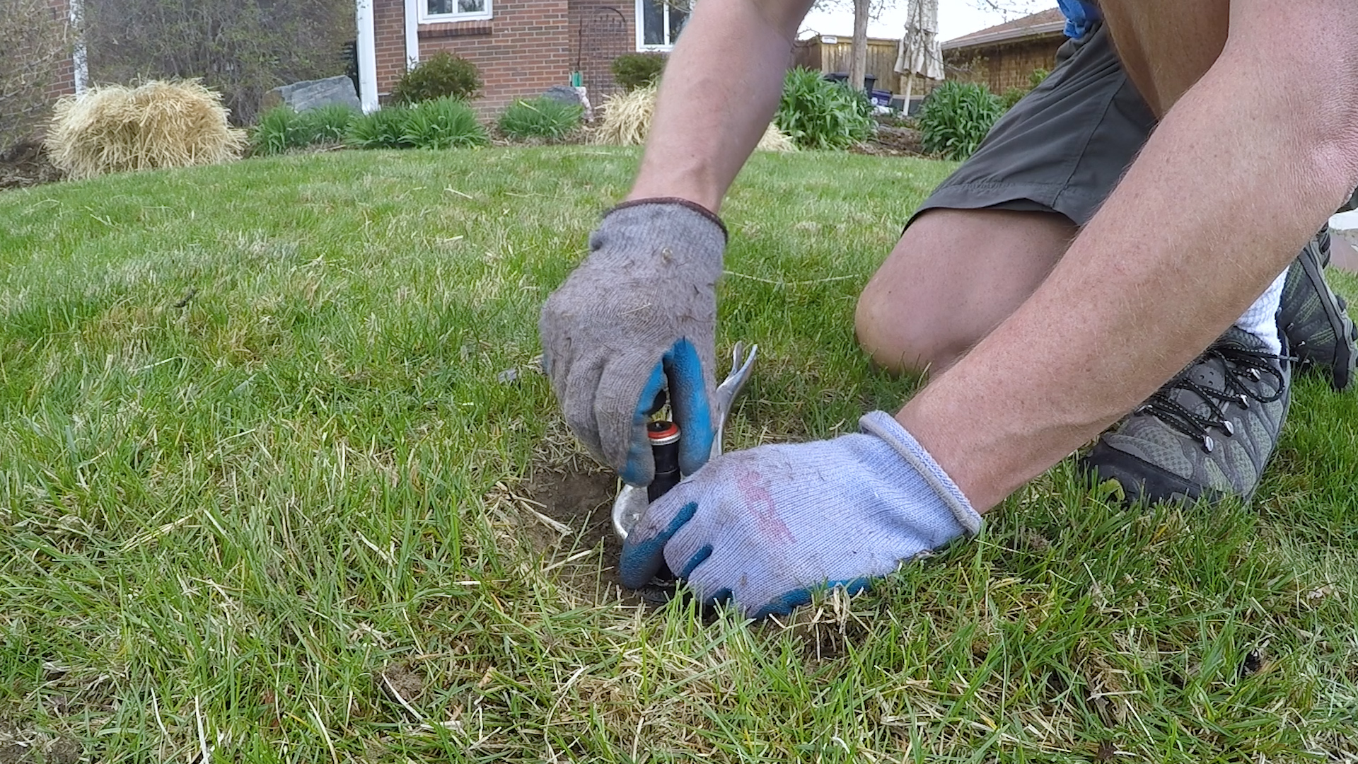 This picture shows a homeowner taking the old sprinkler head off and replacing it with a new one.
