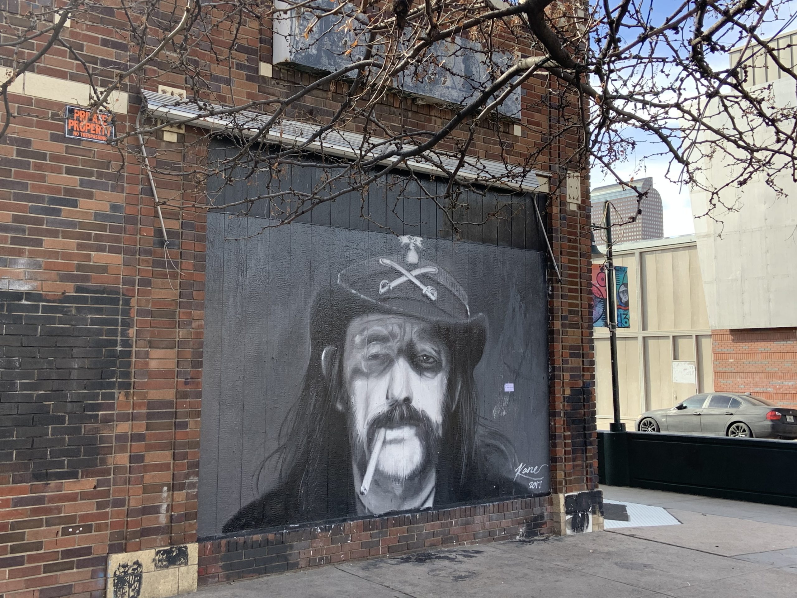 A wall mural of a man, smoking a cigarette, with long hair, mustache, and a cowboy hat.