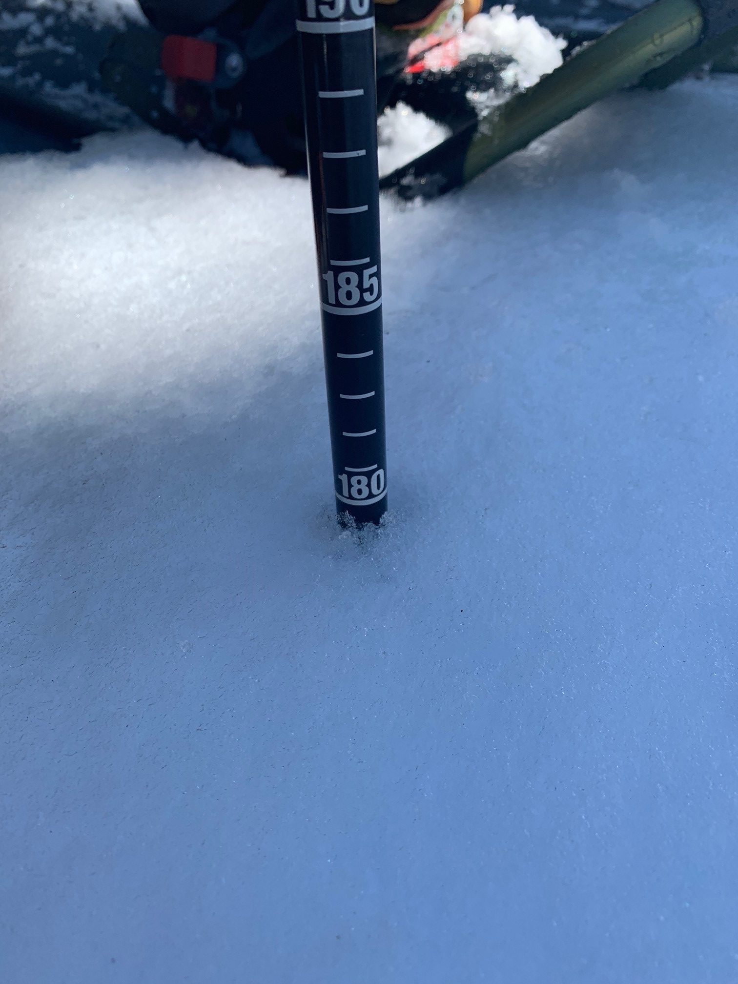 A rod marked with centermeters sticks out of the snow, which reaches to nearly 180 centimeters.