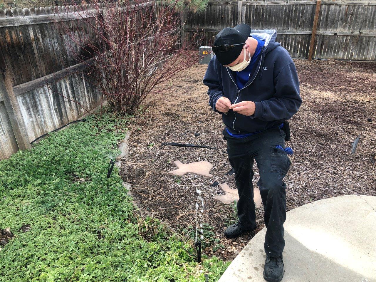 A sprinkler tech dons a mask to assist a homeowner with sprinkler activation in southeast Denver April 23.