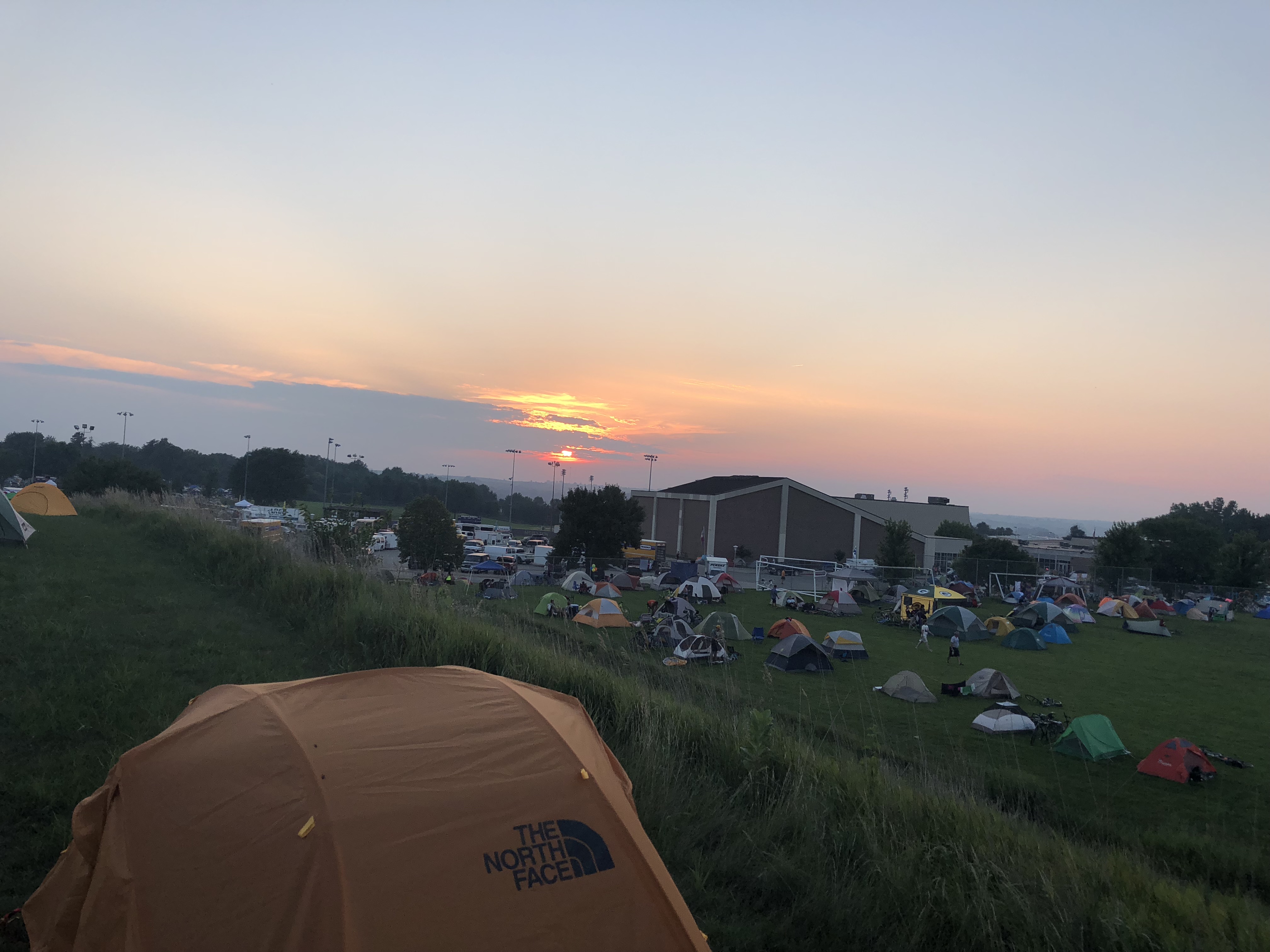 Tents are strewn across a school field in western Iowa under a sunset.