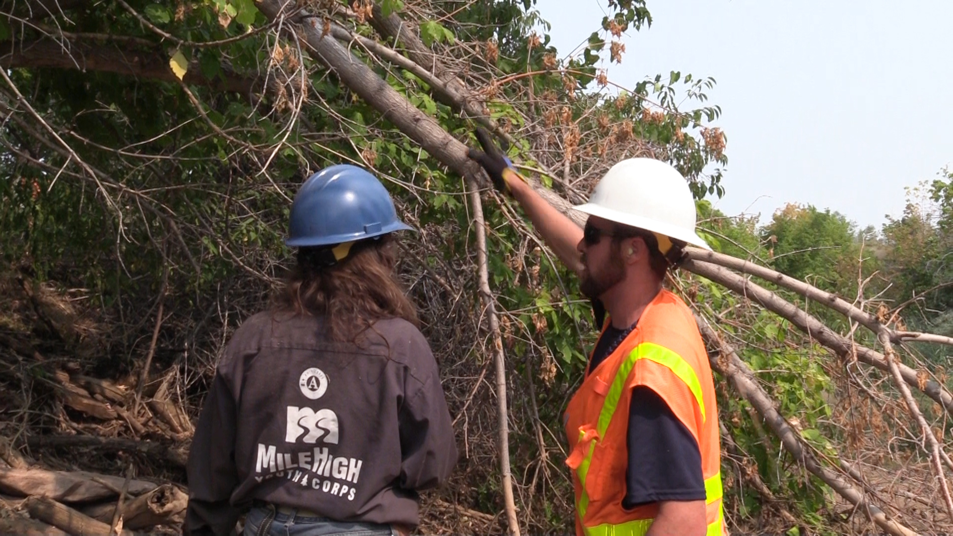 Jesse Hartwell, Mile High Youth Corps member (left), gets advice on trimming a tree branch from Zackery Lane, High Line Canal senior equipment operator at Denver Water.
