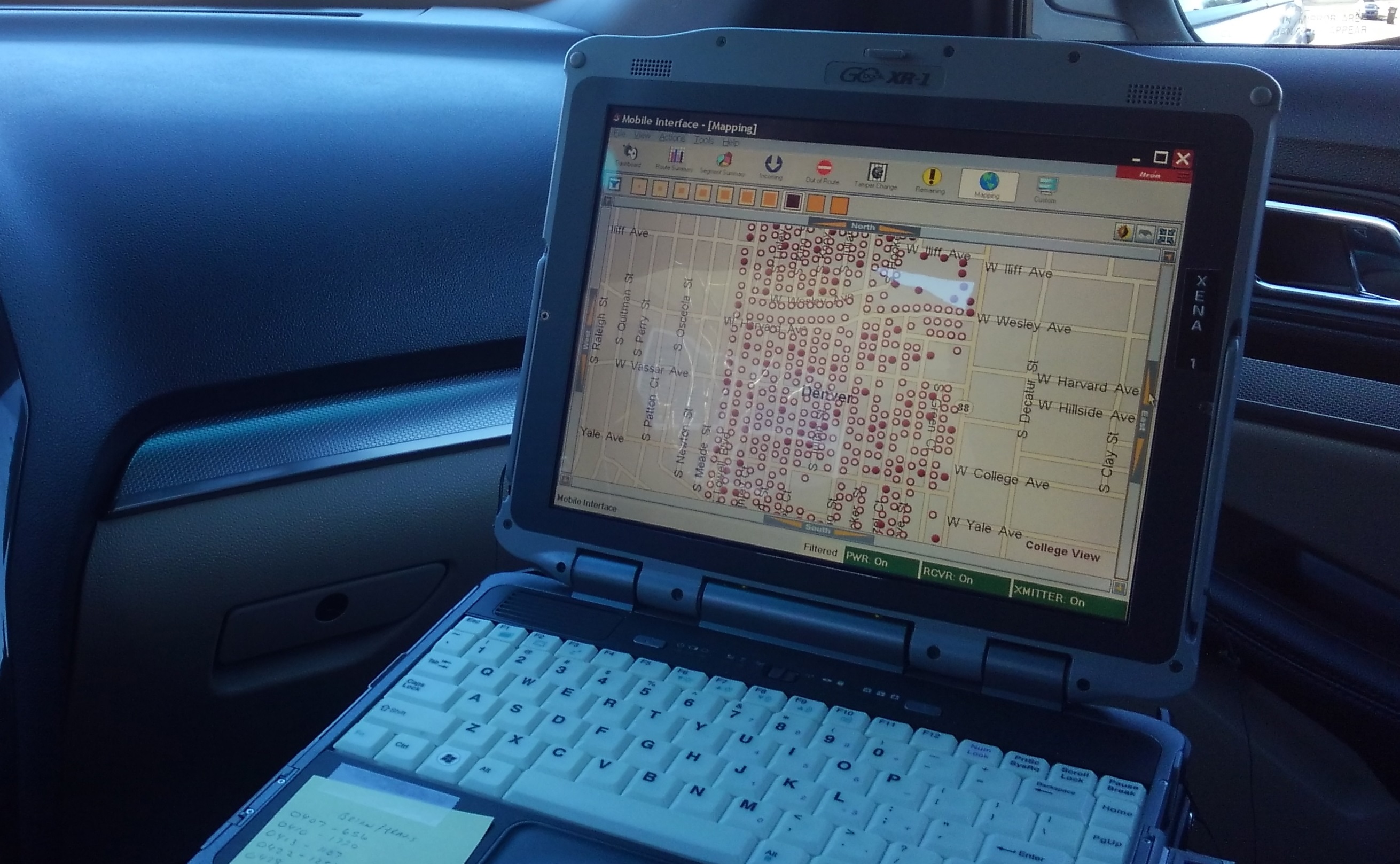 A computer sits on the passenger seat of a meter reading vehicle with a Google-like map filled with tiny dots indicating meter reads that need to be captured at each property.