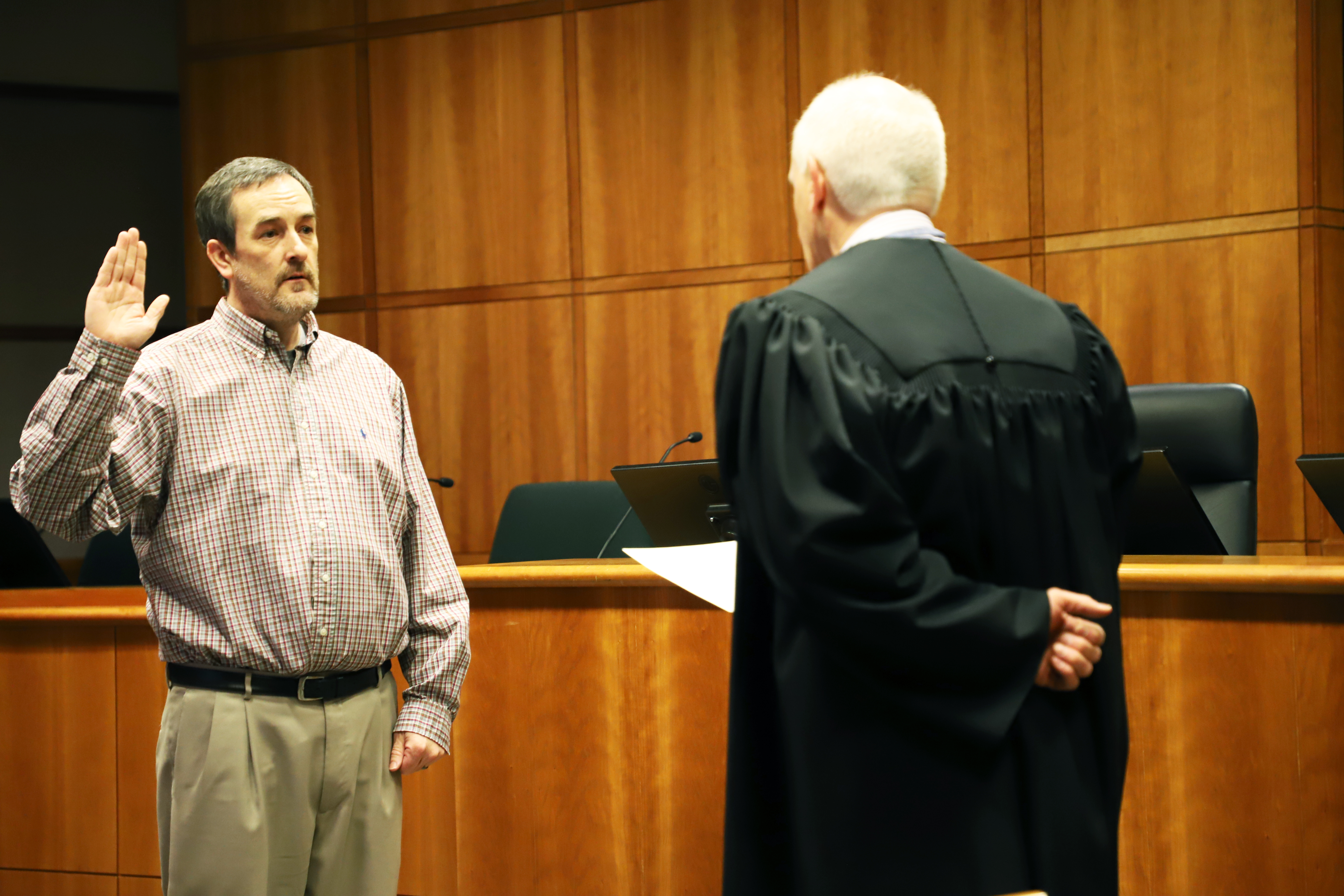 Bryan Douglass stands with a judge, right hand raised, as he takes the oath of office.