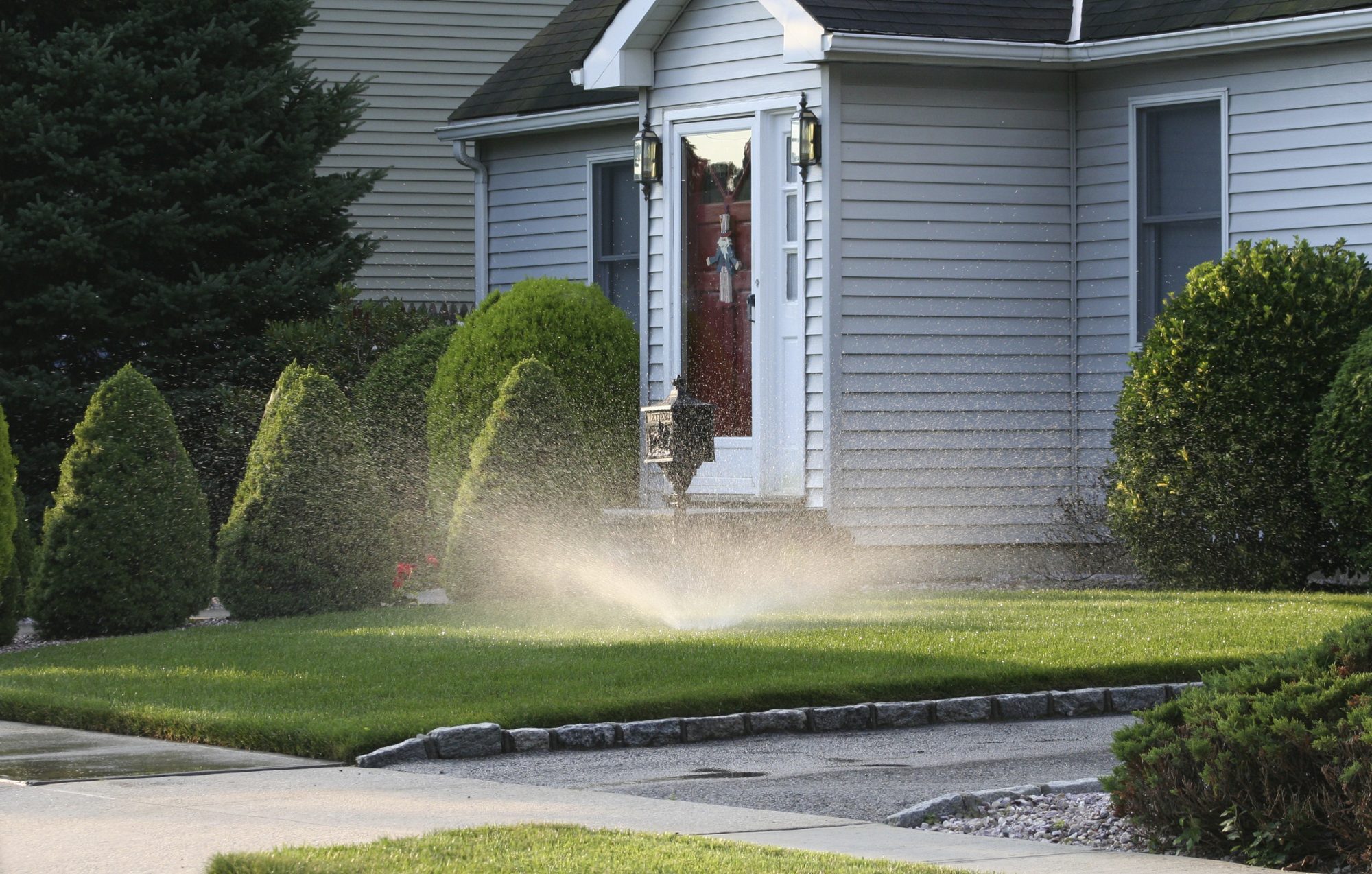 House with sprinkler watering the lawn