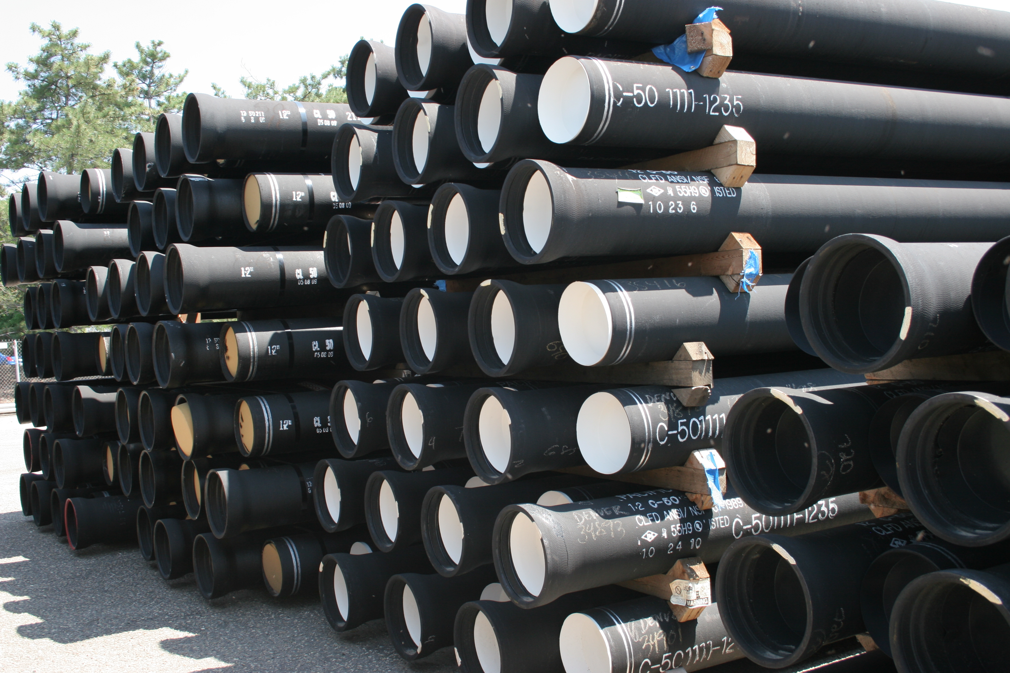 black pipes are stacked 7 rows high, with wood blocks between them.