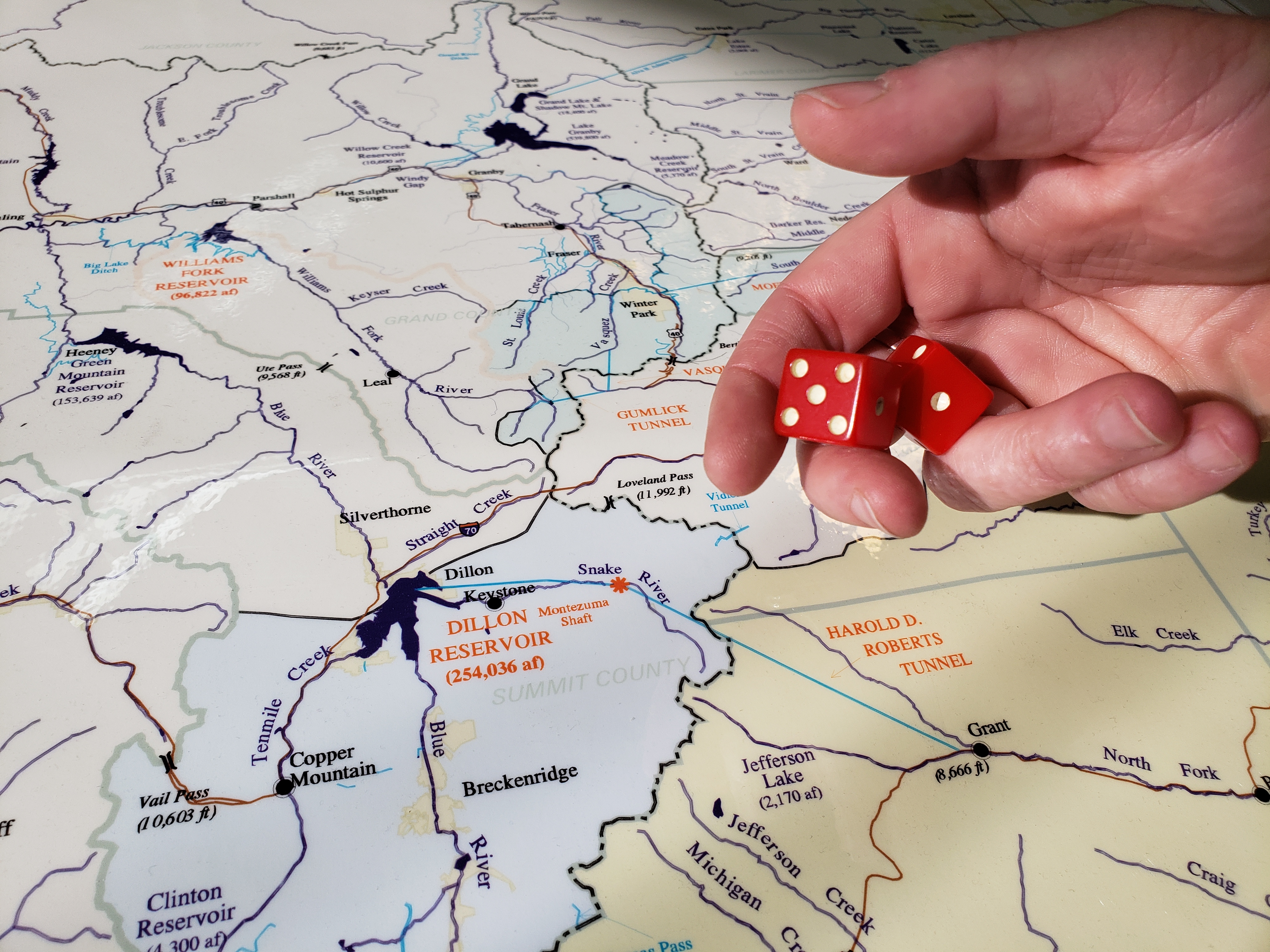 A map of Denver Water's collection systems with a hand holding a pair of dice.