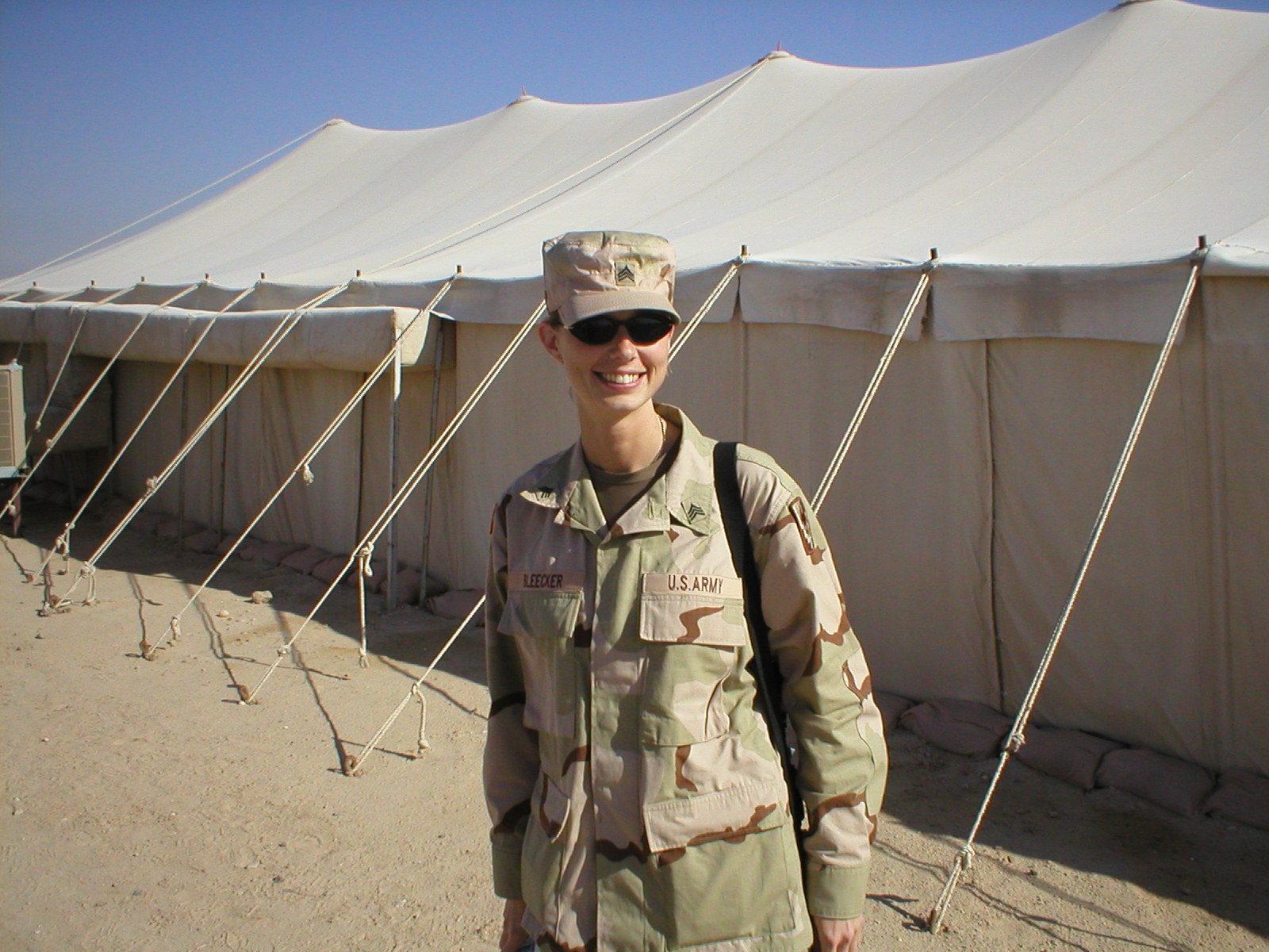 This photo shows a woman in military uniform in front of a tent.